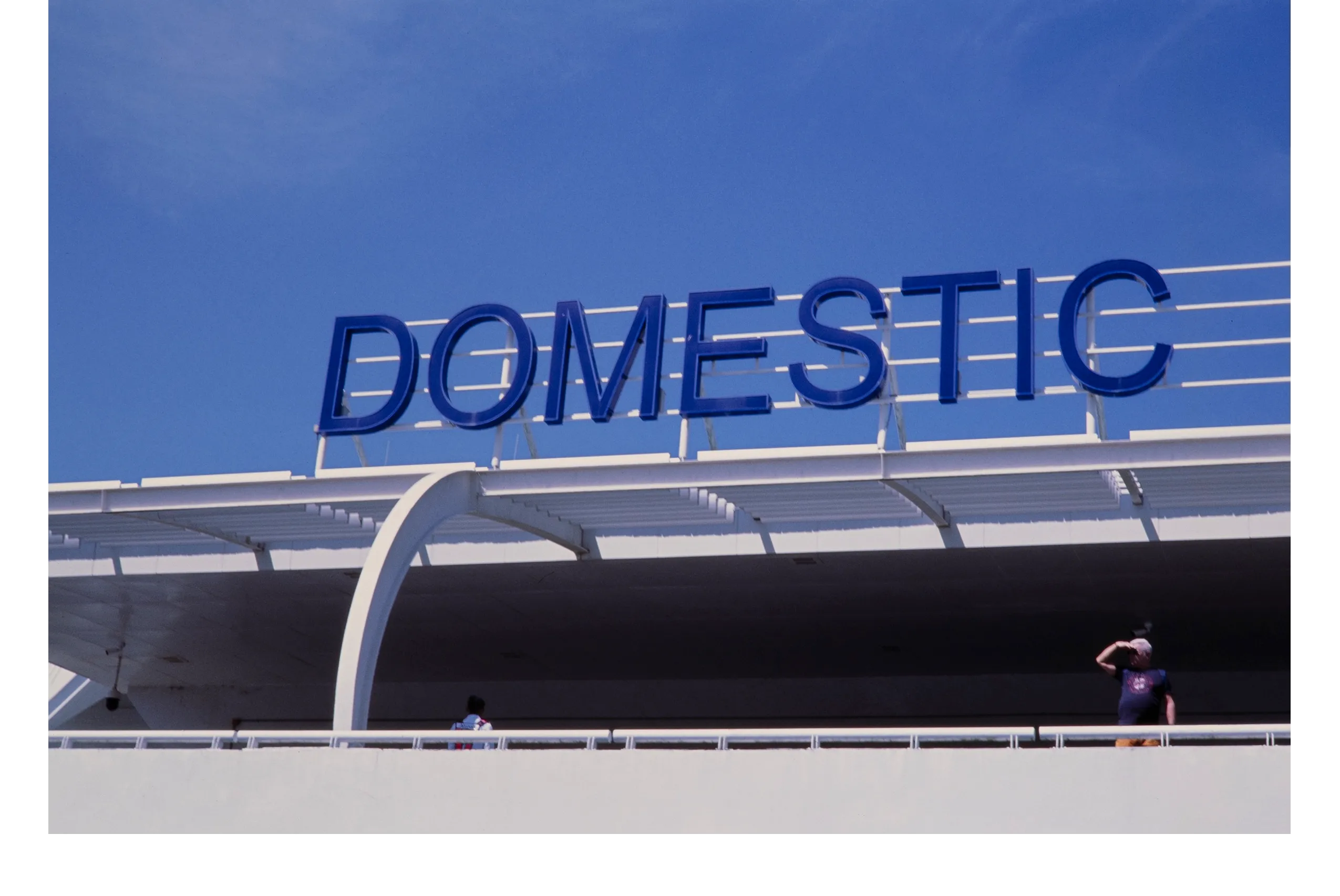 man looks out over a ledge, at an airport